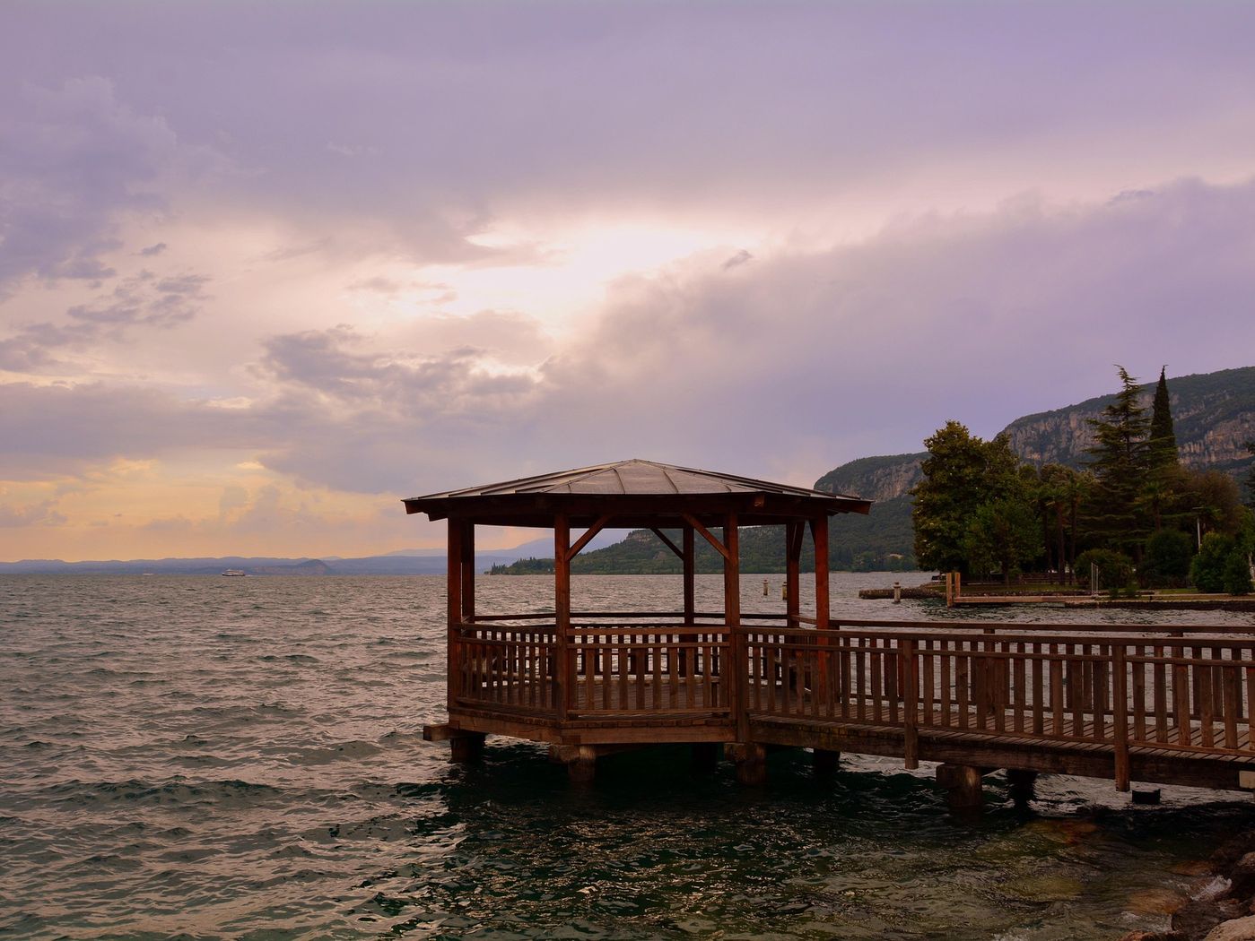 Wooden gazebo on a private dock at dusk over a still lake
