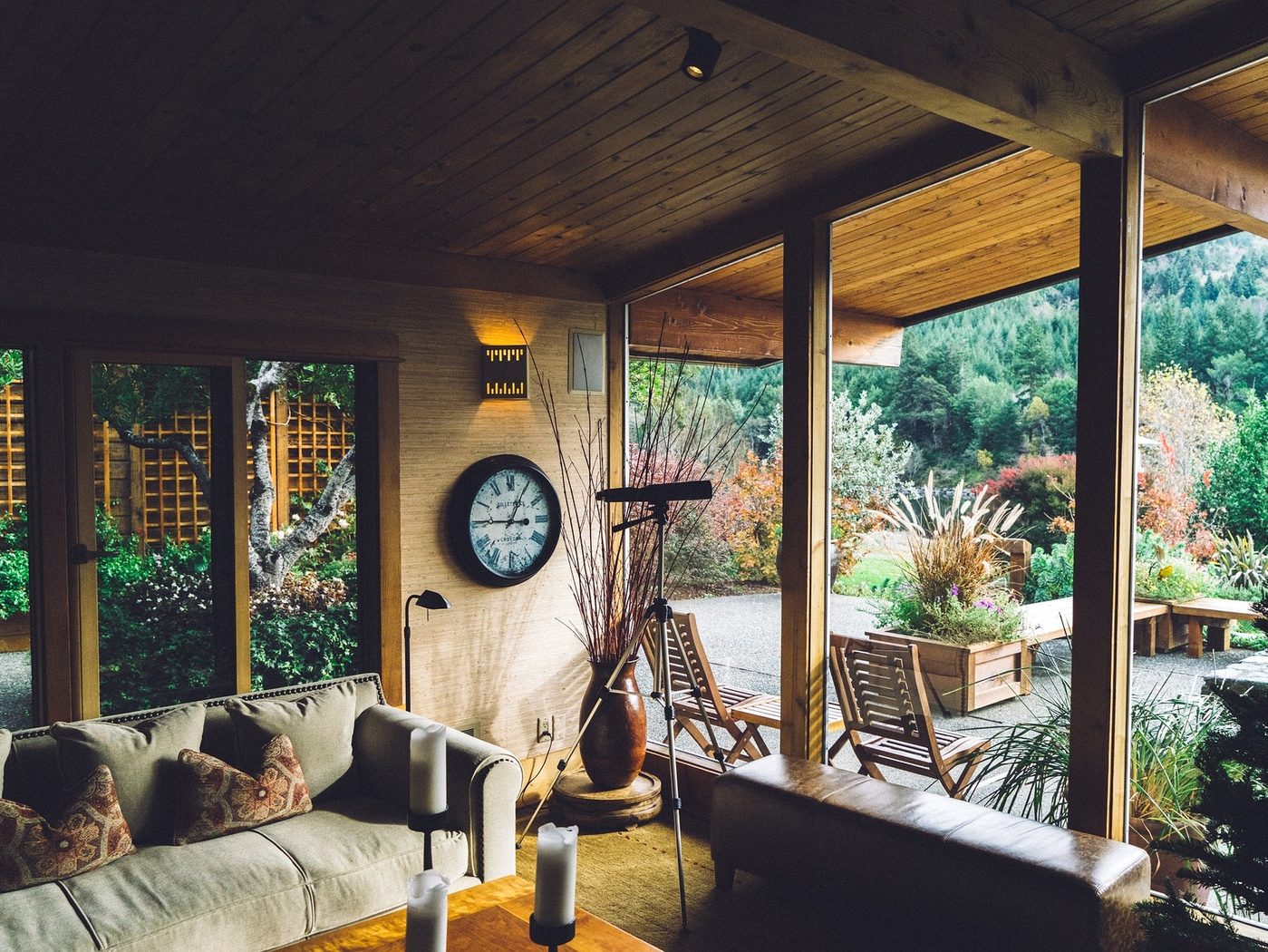 Covered porch with a long sofa and a fireplace looking out to a garden